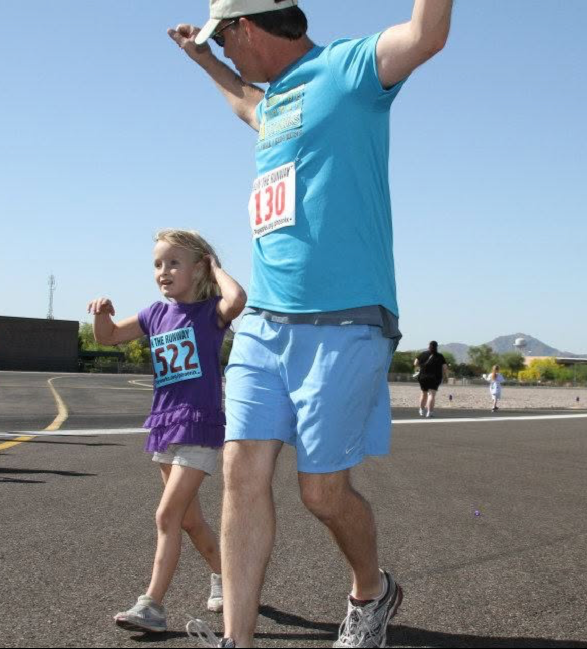 Dad and daughter running together on the runway