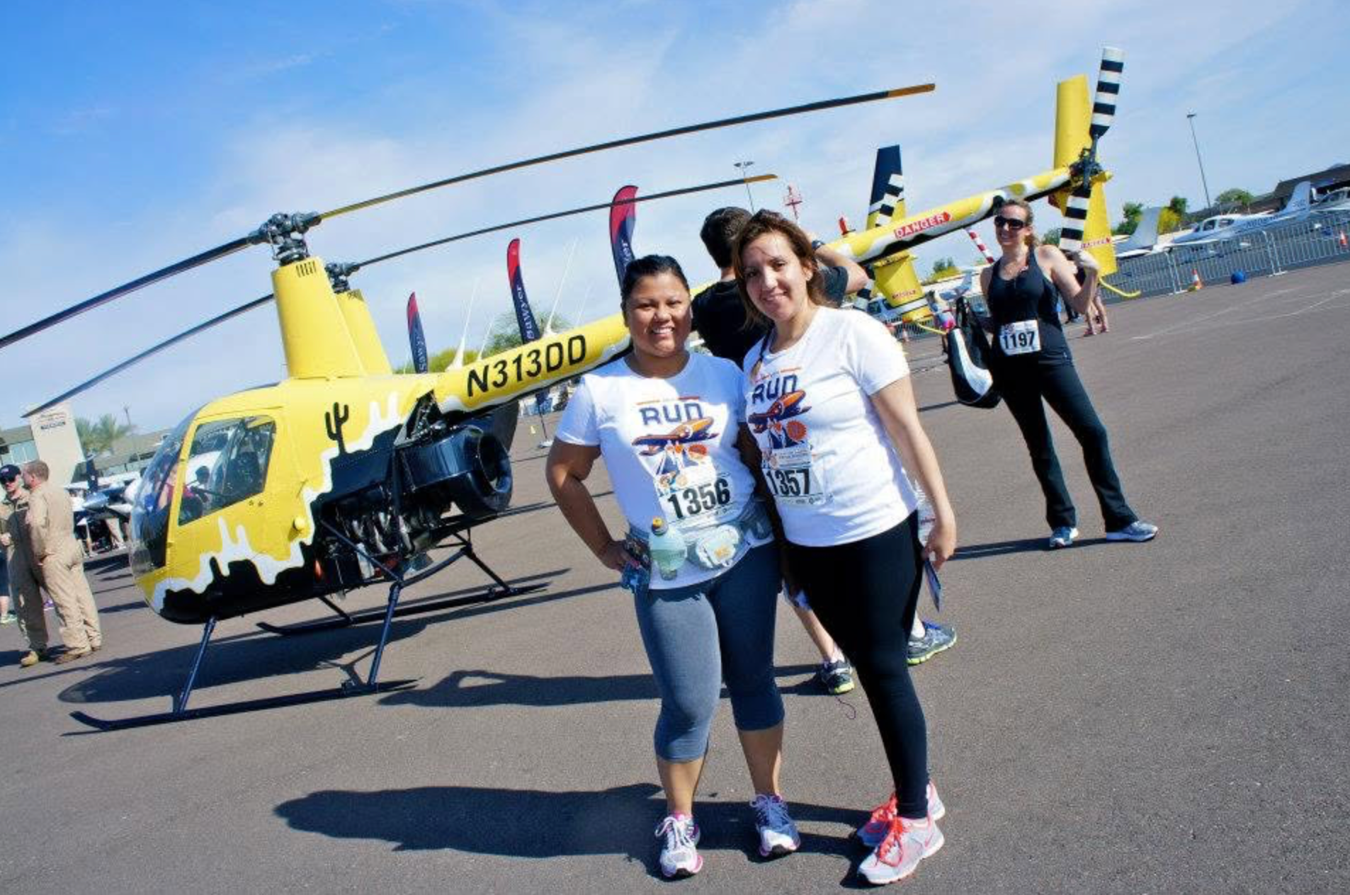 Runners posing with helicopter on the tarmac